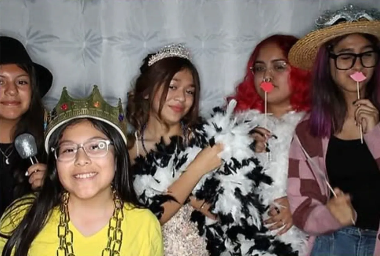 A group of friends with crowns, boas and props in the photo booth